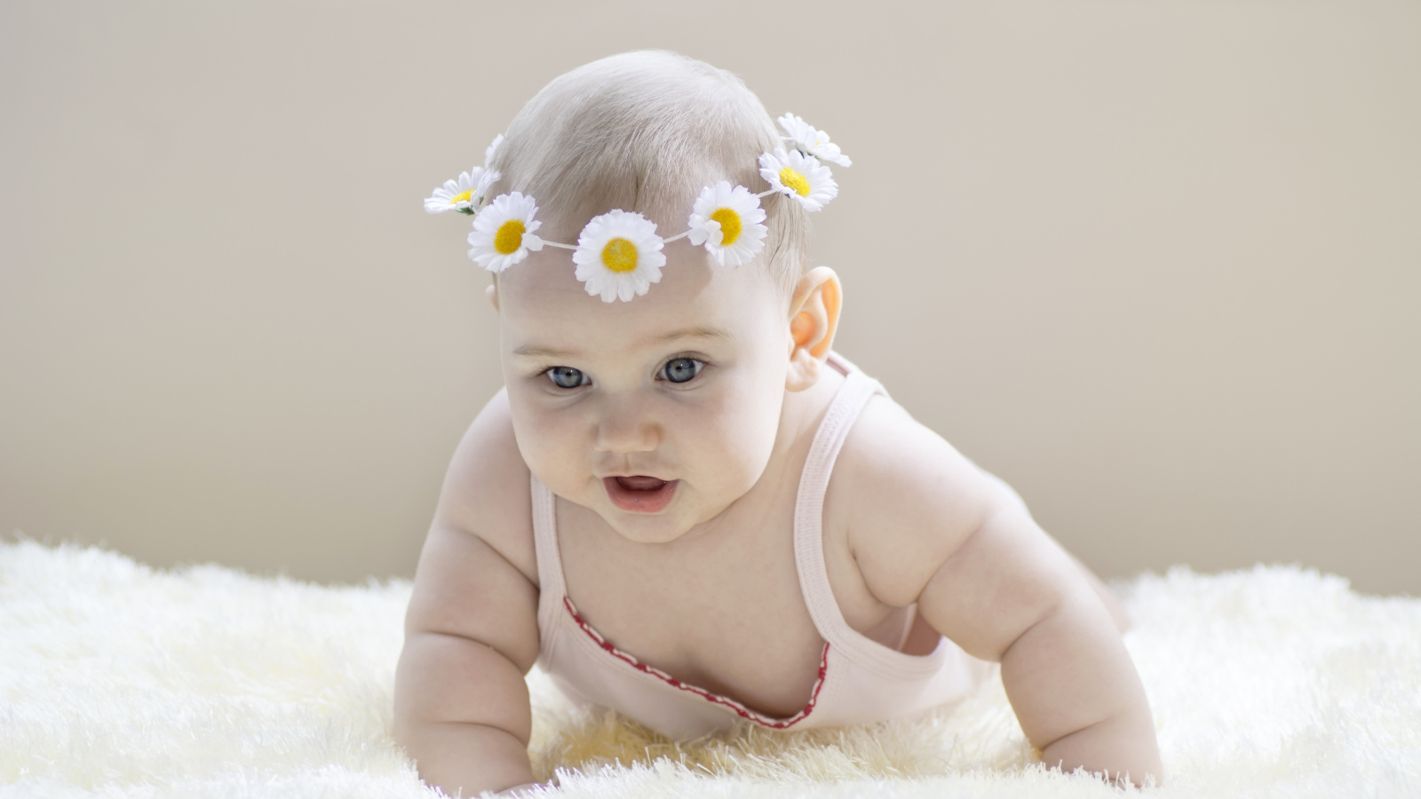 Грудной ребенок с венком из белых ромашек на голове