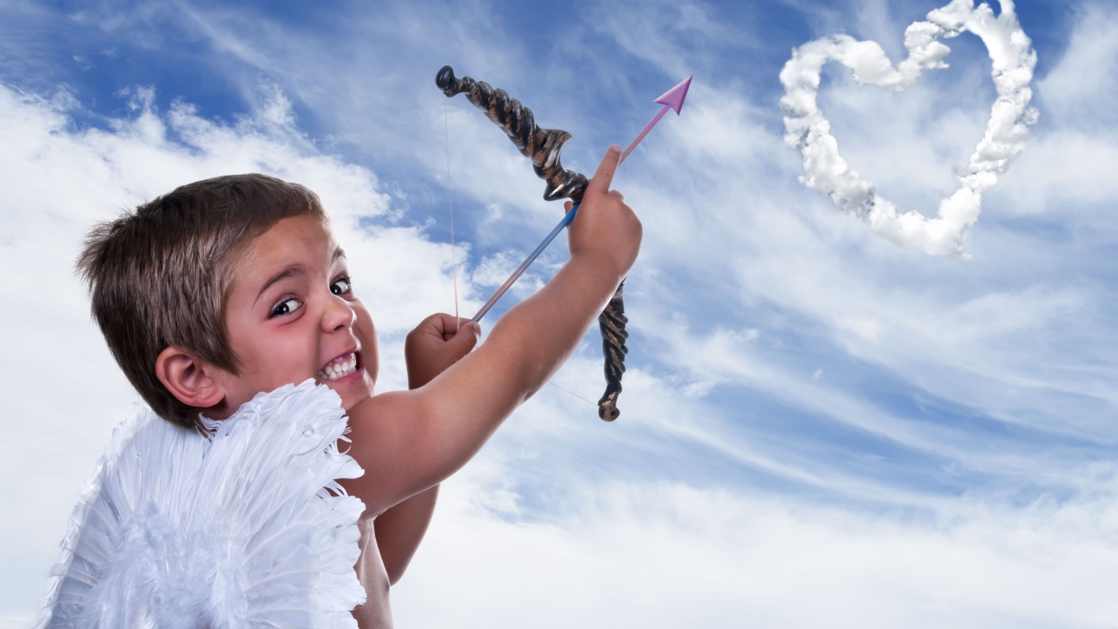 Мальчик в костюме купидона пускает стрелу в небо