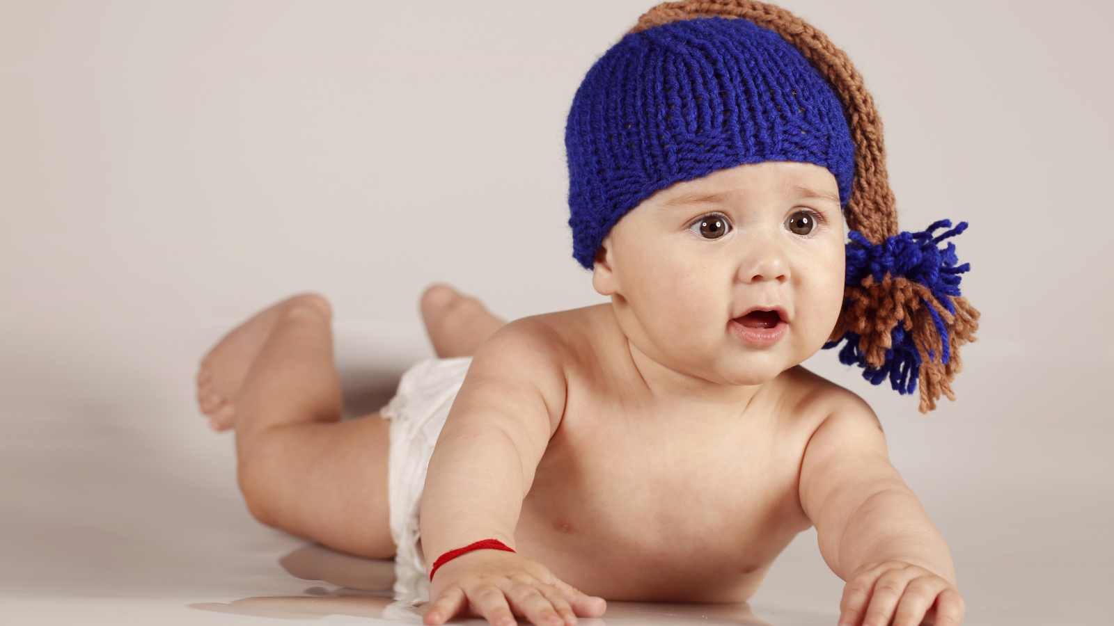 Грудной кареглазый ребенок в вязаной шерстяной шапке