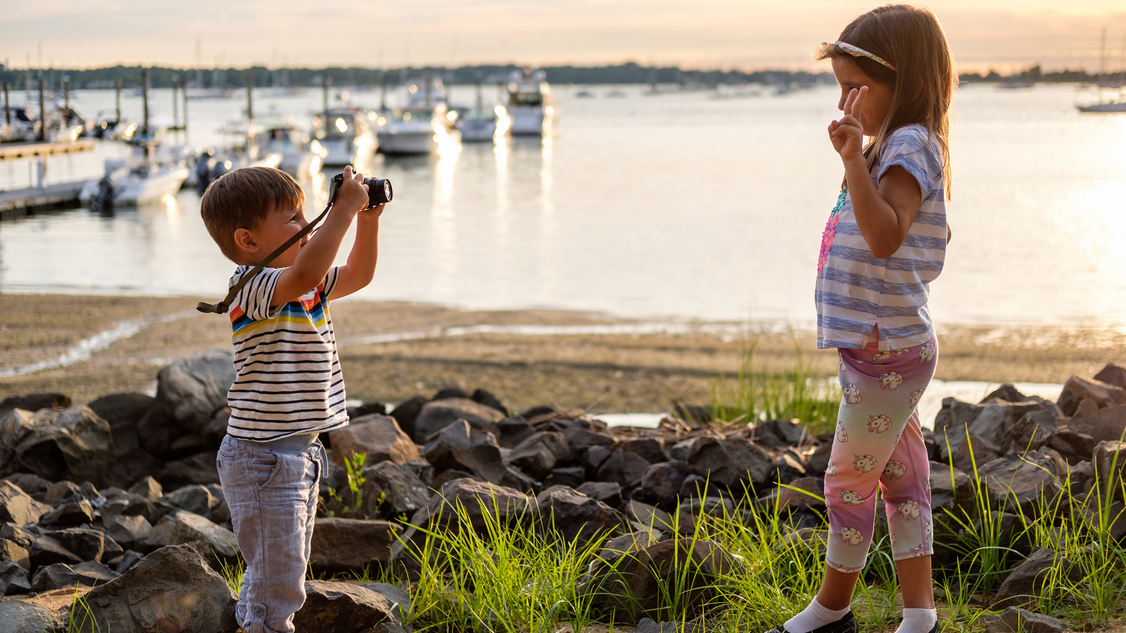 Маленький мальчик фотографирует девочку на берегу