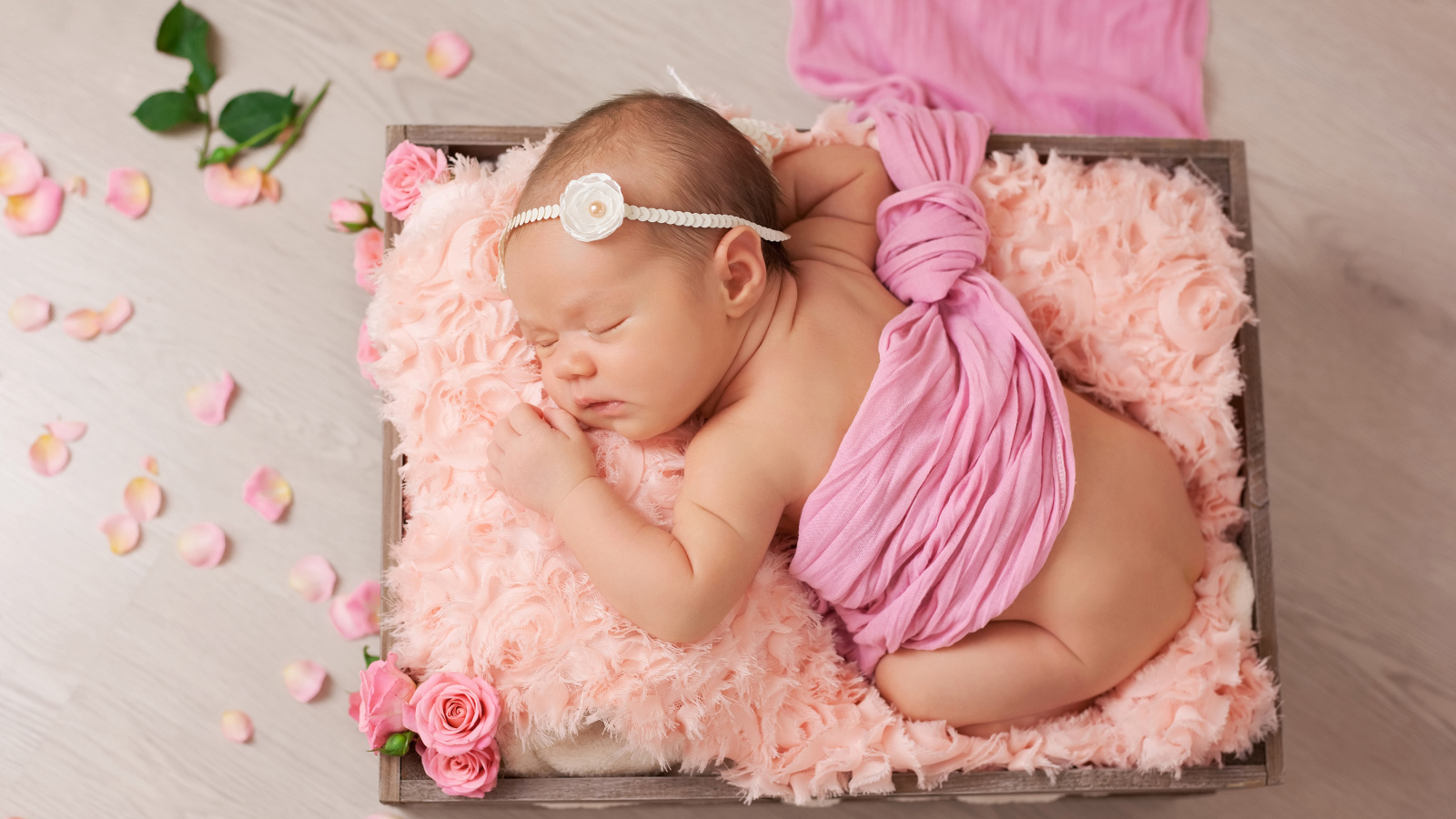 Спящий младенец с розовыми лепестками роз