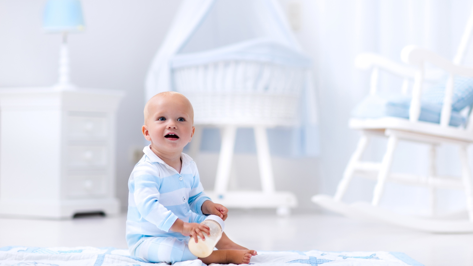 Маленький голубоглазый мальчик сидит на полу в комнате