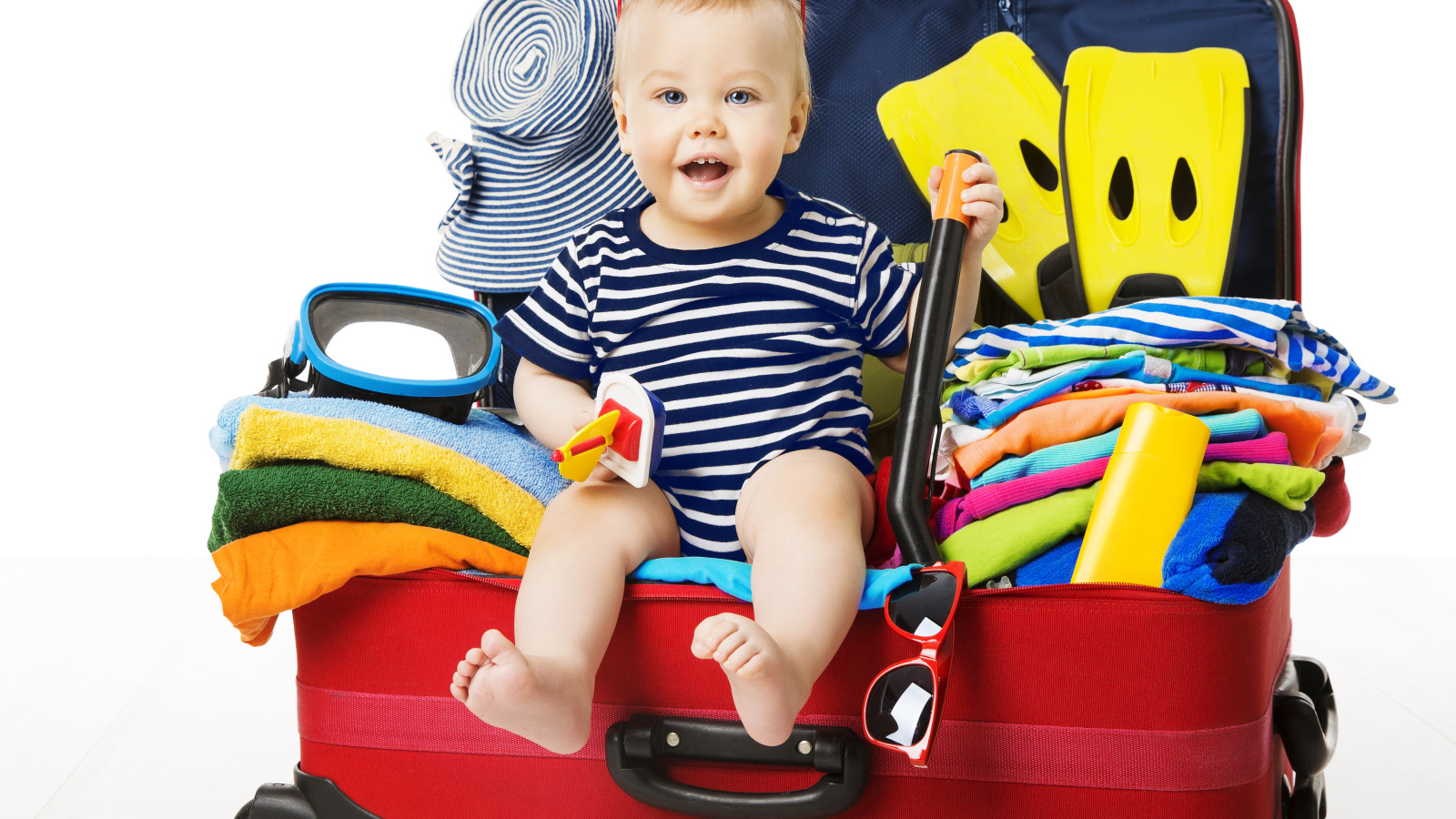 Маленький ребенок сидит в большом красном чемодане с вещами