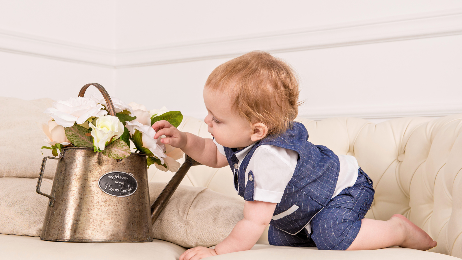 Маленький ребенок рассматривает цветы в железной лейке