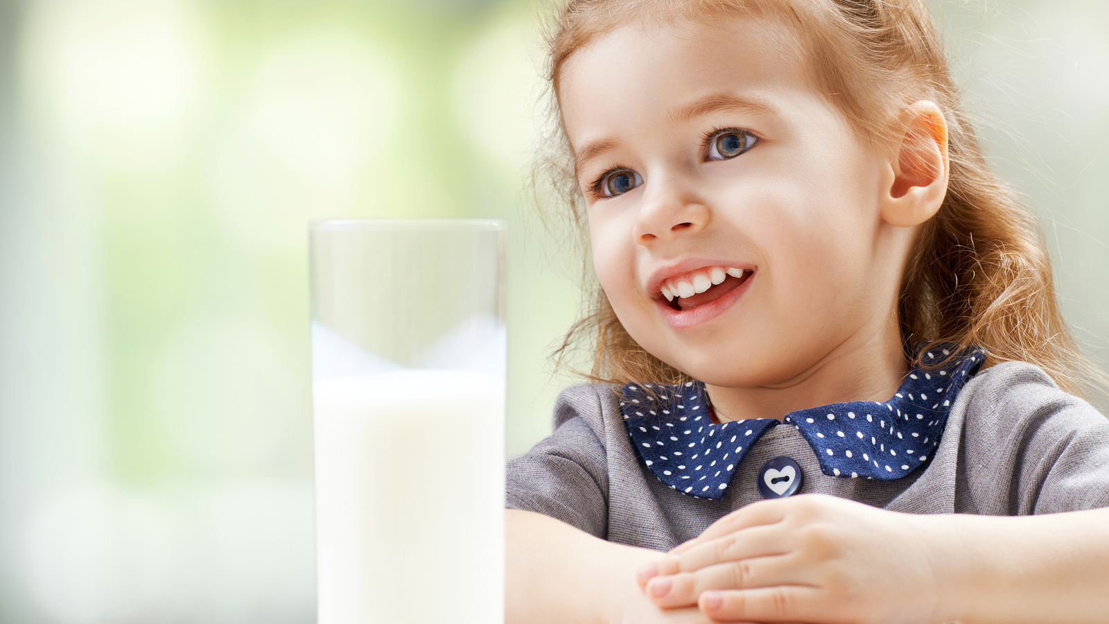 Красивая кареглазая девочка со стаканом молока