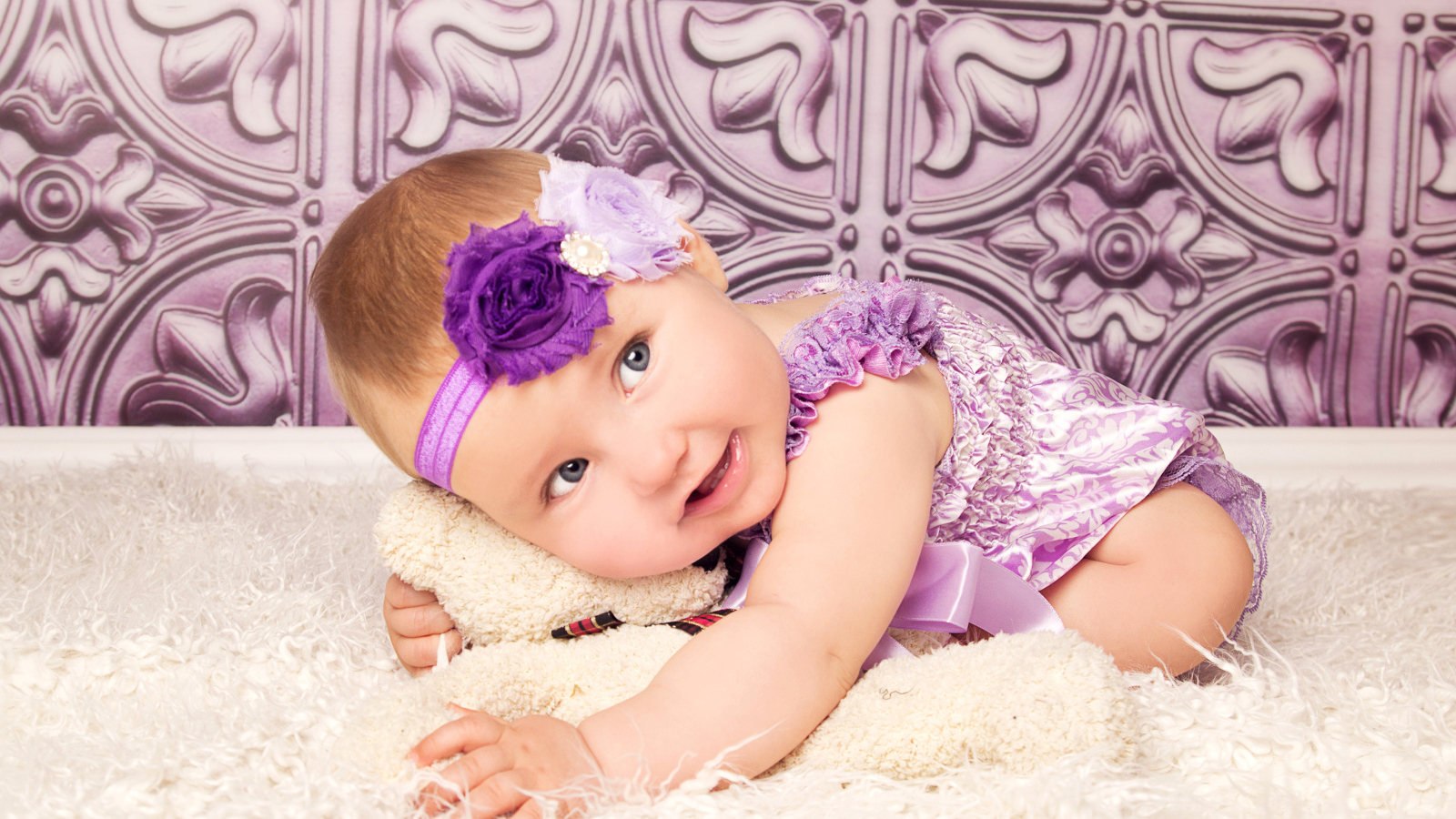 Красивая маленькая девочка в фиолетовом костюме с плюшевым мишкой