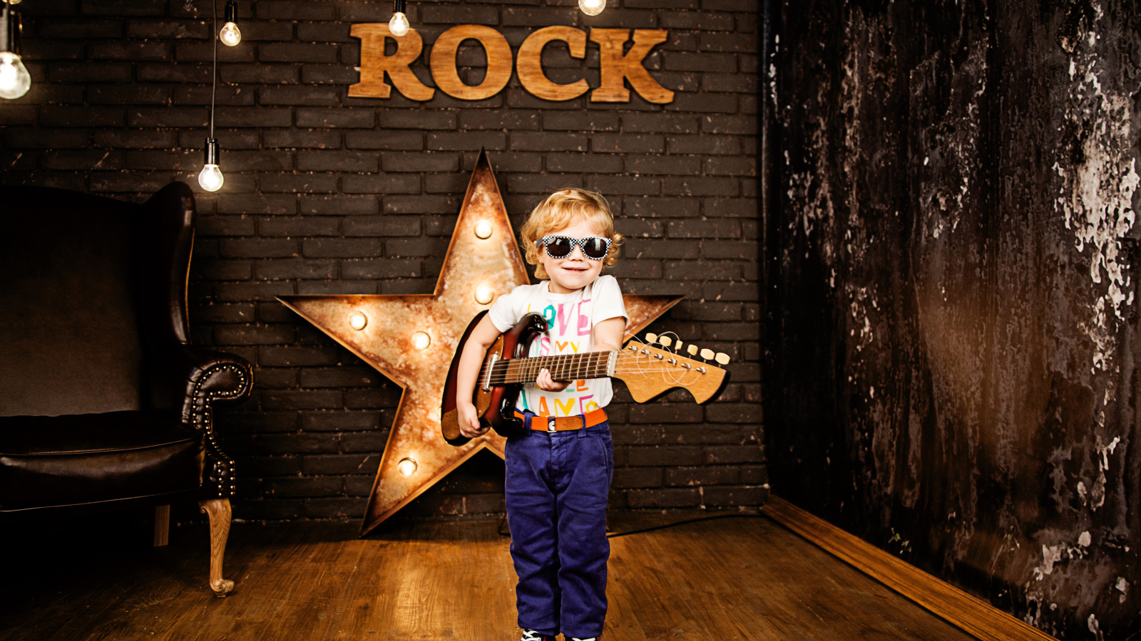 Маленький мальчик в модных очках с гитарой