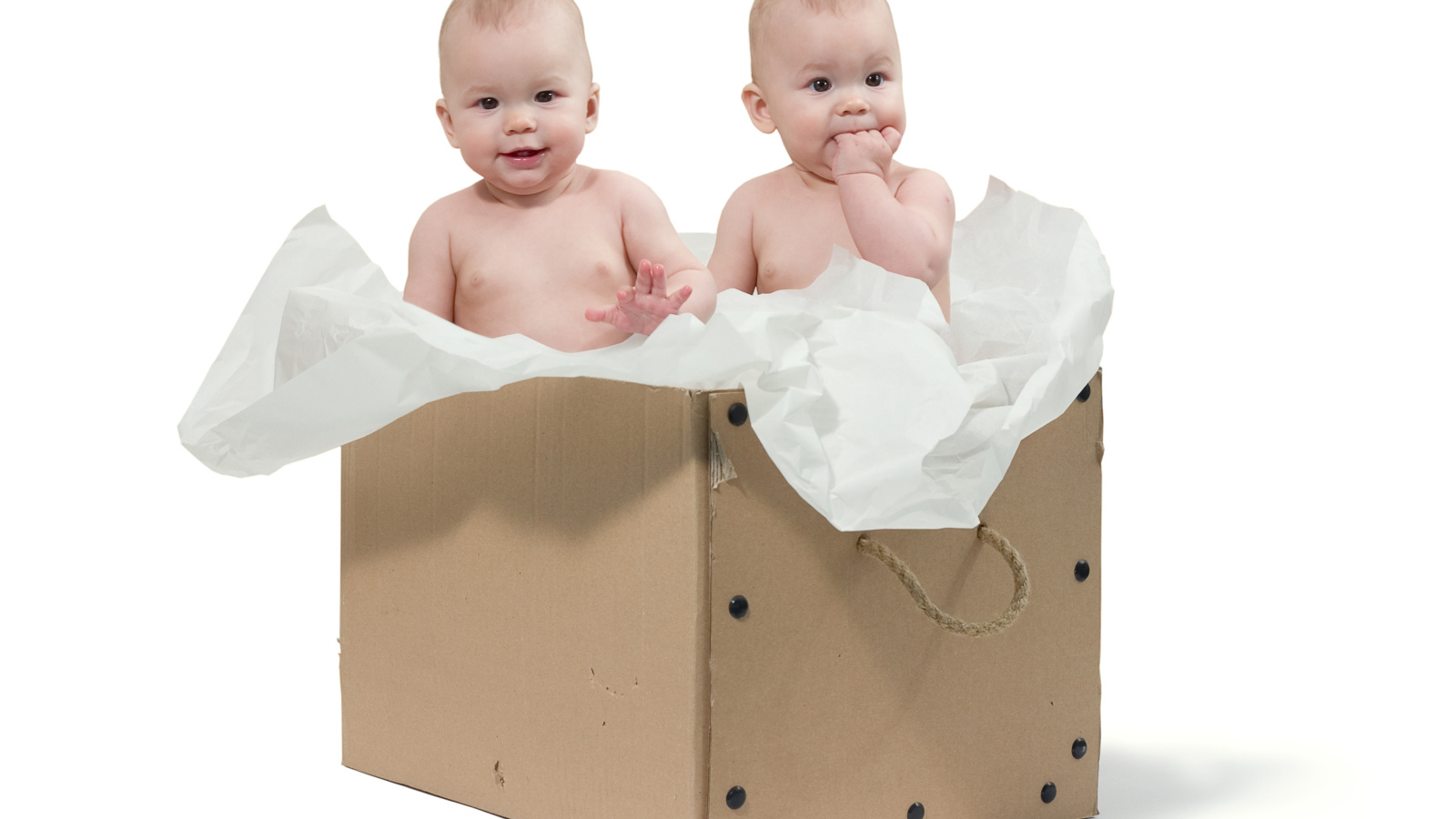 Маленькие дети сидят в картонной коробке с бумагой