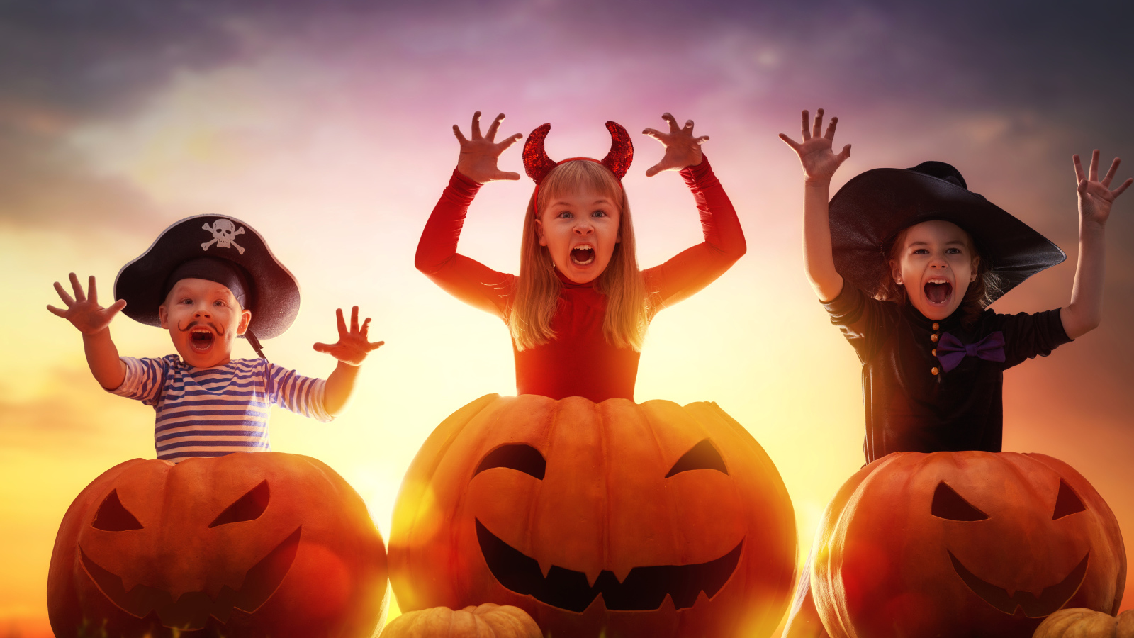 Маленькие дети в костюмах на Хэллоуин с большими тыквами