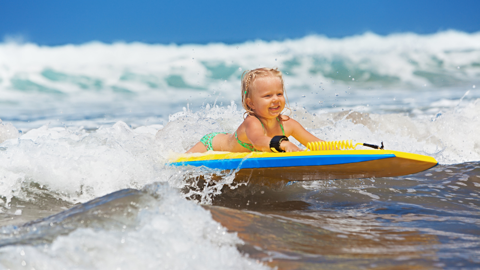 Маленькая девочка в море на доске для серфинга