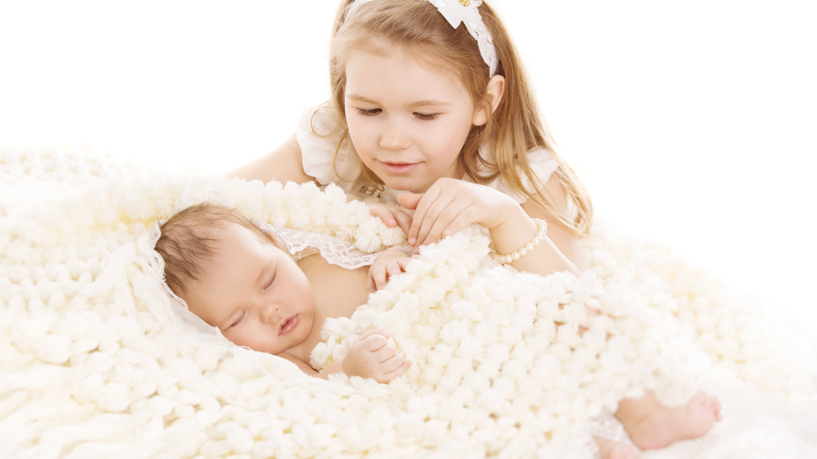 Маленькая девочка в белом со спящим младенцем на белом фоне