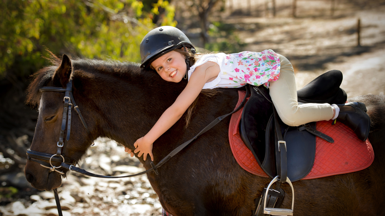 Маленькая девочка в шлеме верхом на пони
