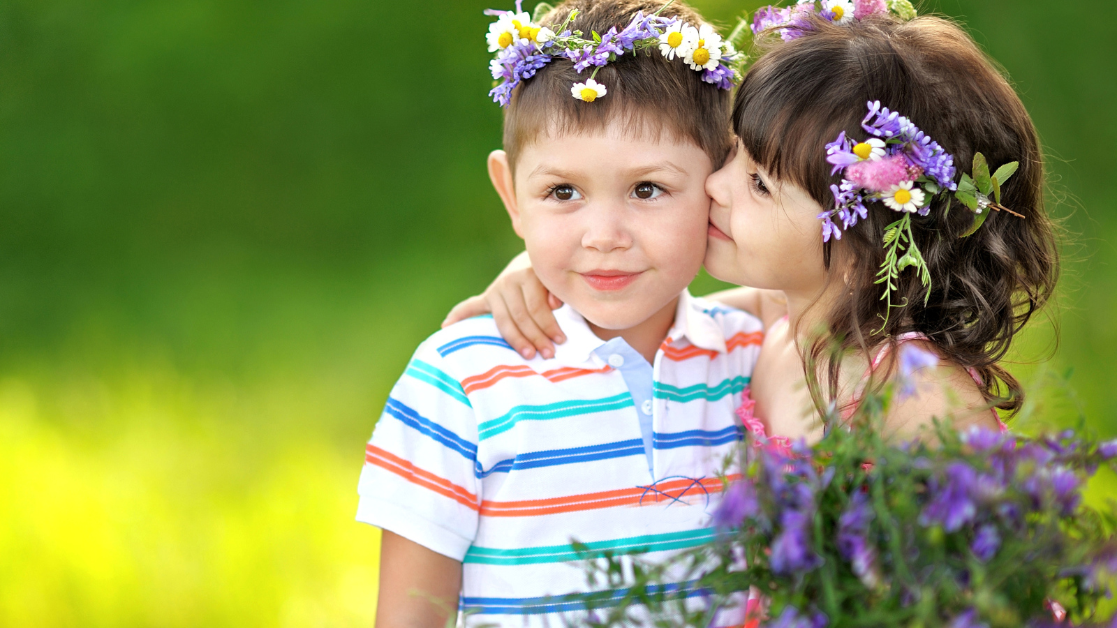 Маленькая девочка с букетом полевых цветов целует мальчика