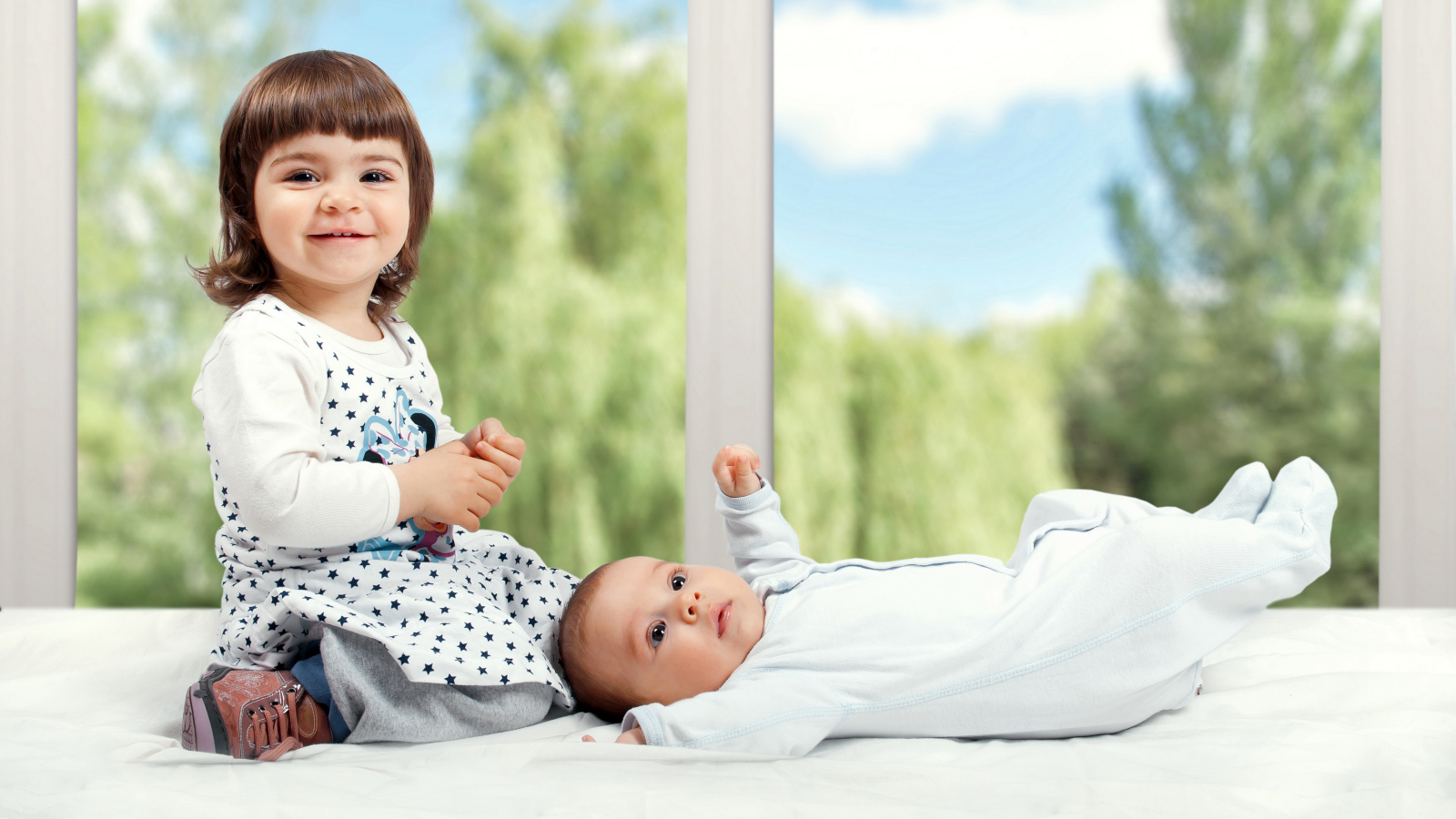 Маленькая улыбающаяся девочка с грудным ребенком