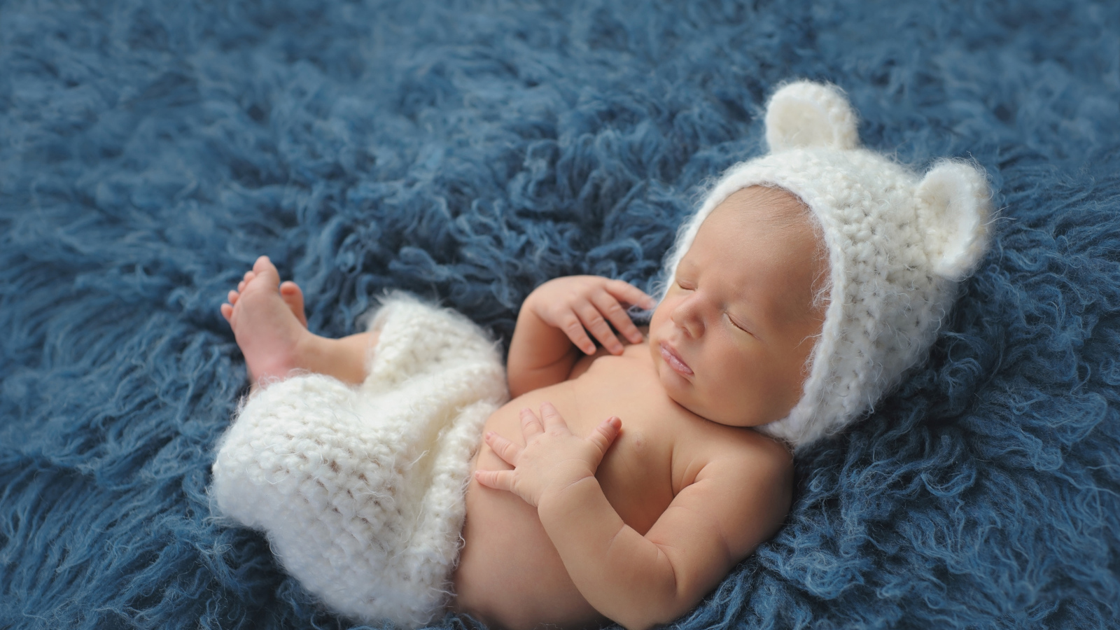 Спящий грудной ребенок в белом костюме медвежонка