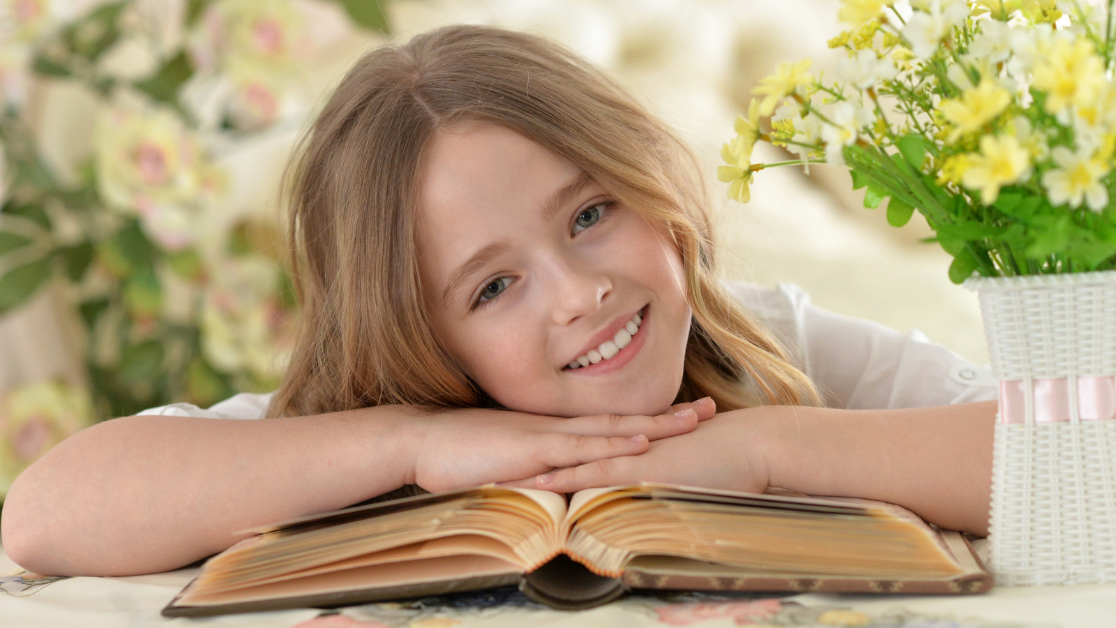 Улыбающаяся русоволосая девочка с книгой