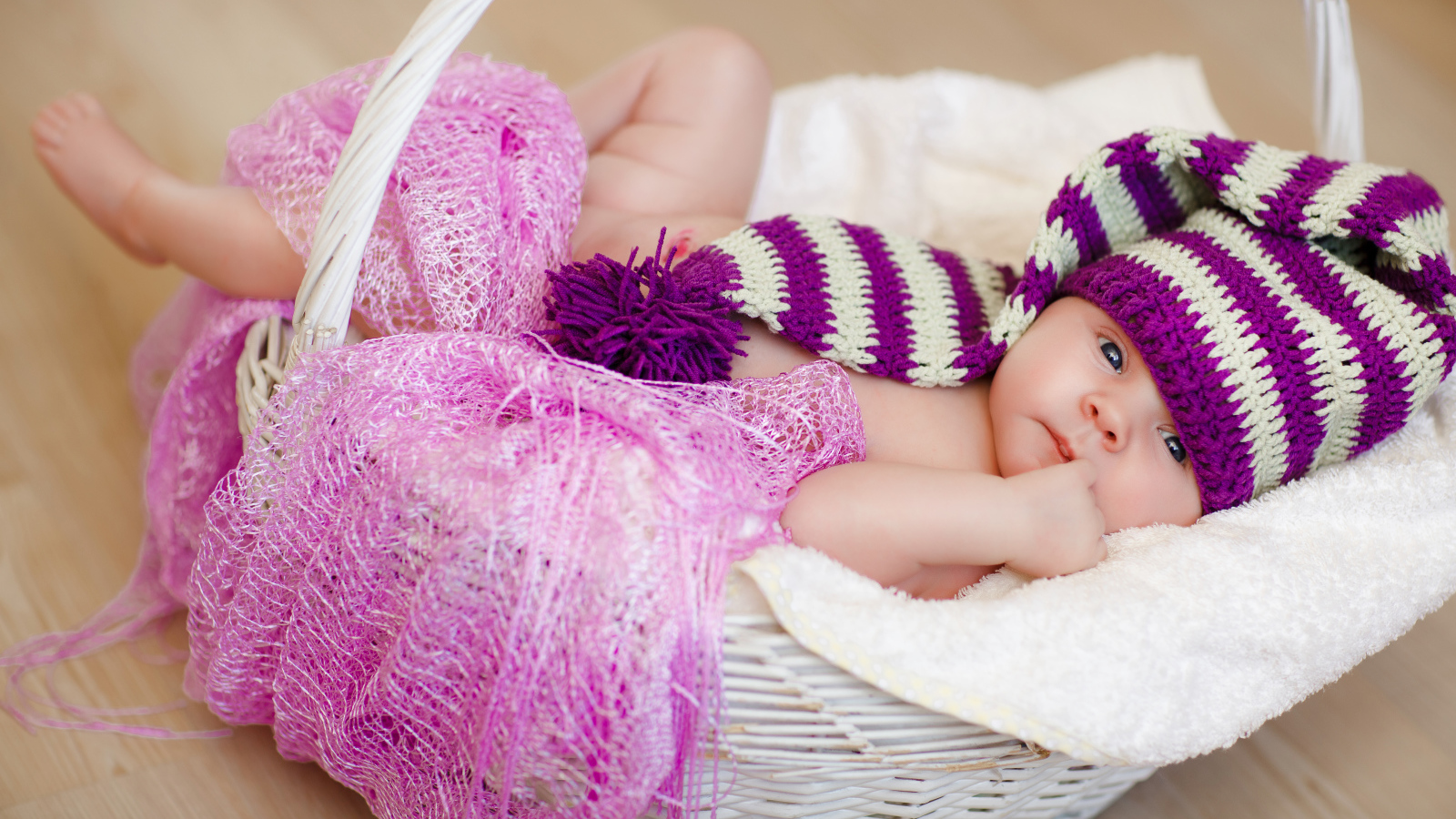 Младенец в красивой вязаной шапке лежит в корзине