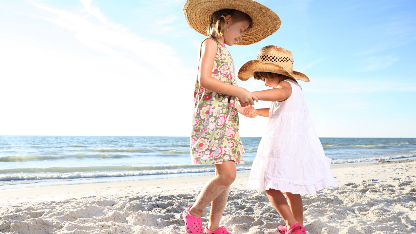 Две маленькие девочки танцуют на песке на пляже