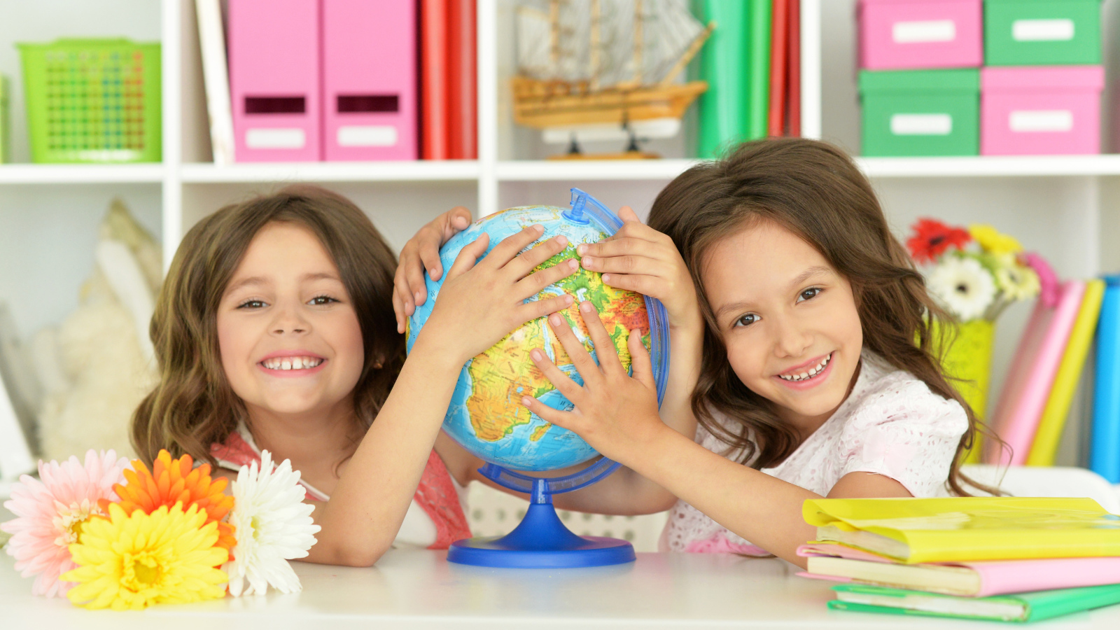 Две маленькие девочки школьницы с глобусом  в руках