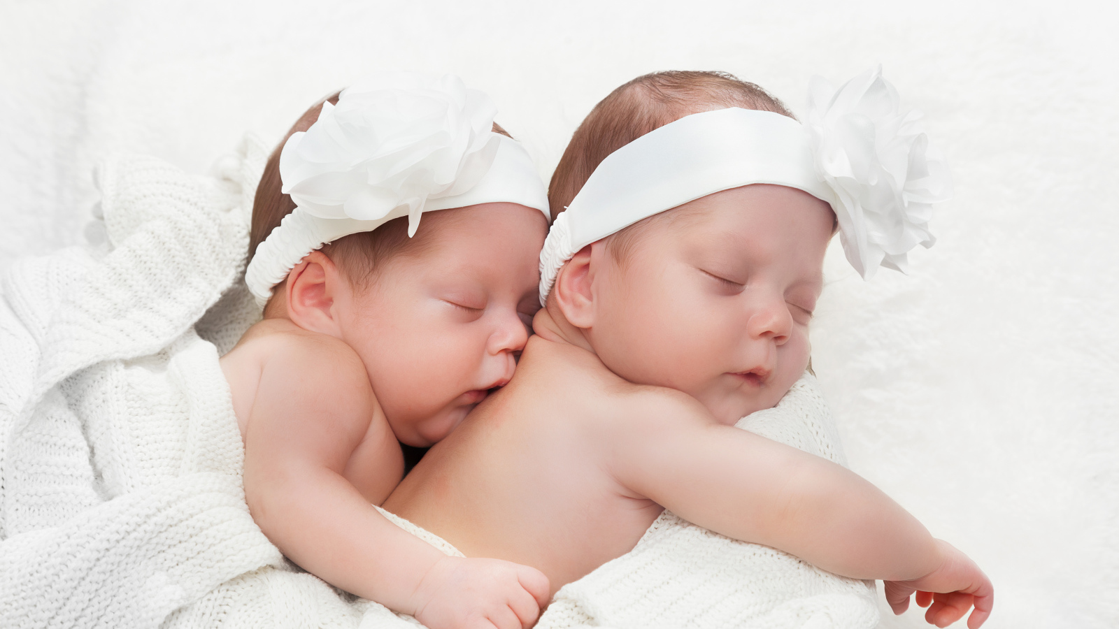 Два спящих младенца с большими белыми цветами на голове