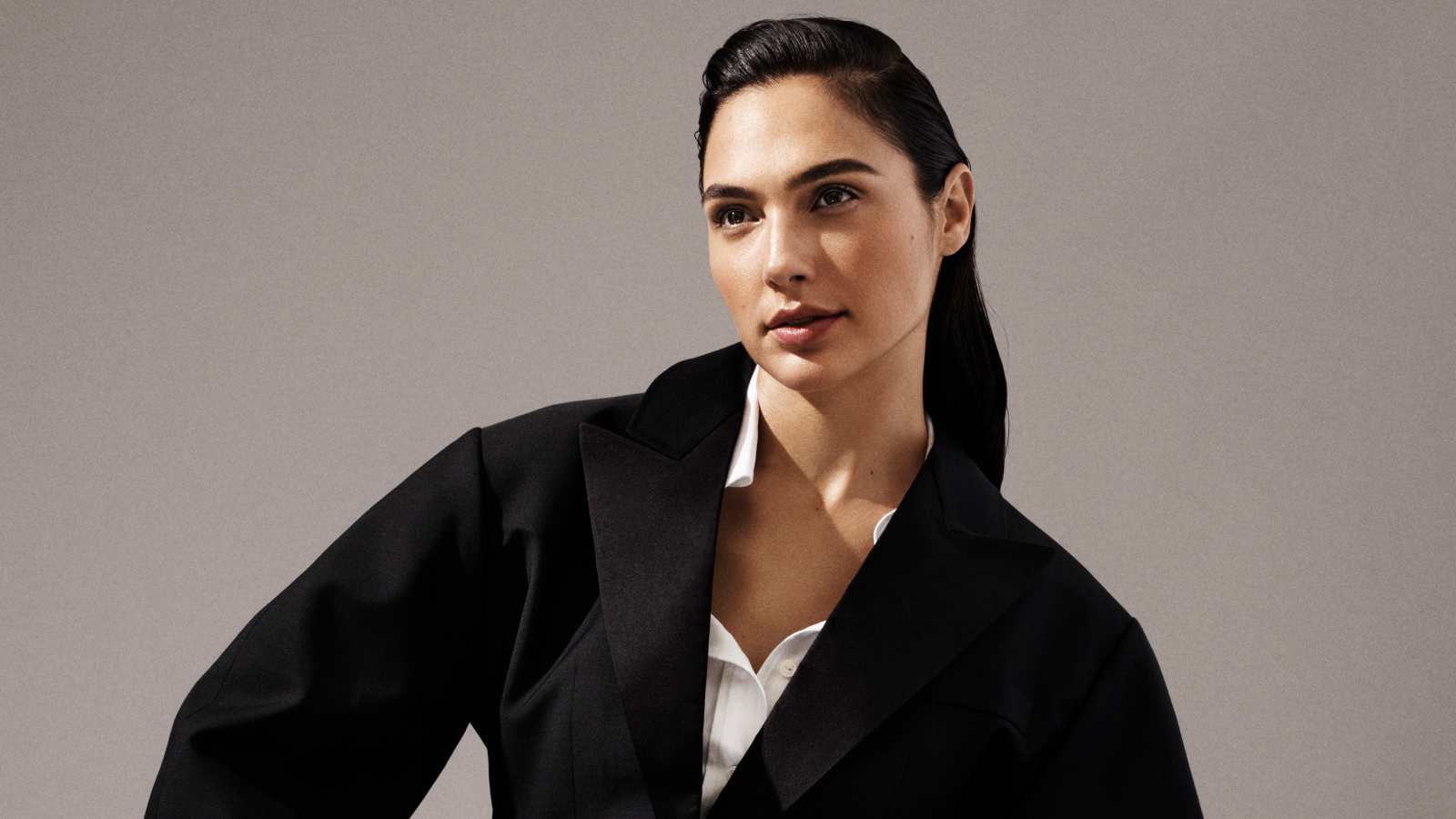 Актриса Галь Гадот в черном пальто на сером фоне
