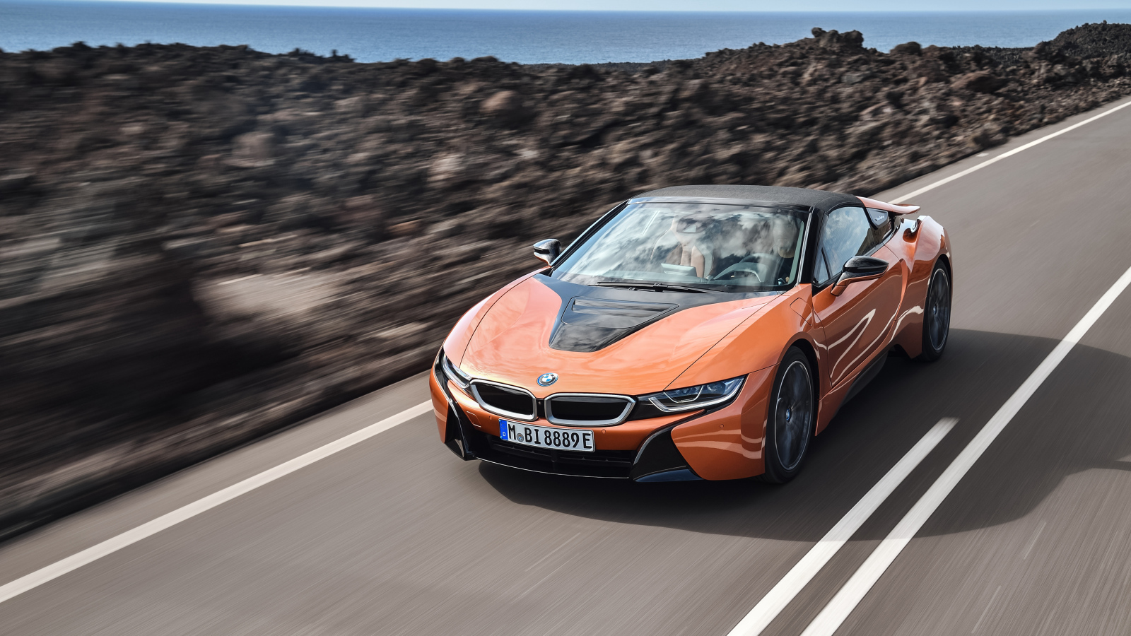 Оранжевый автомобиль BMW i8 Roadster, 2018 на скорости