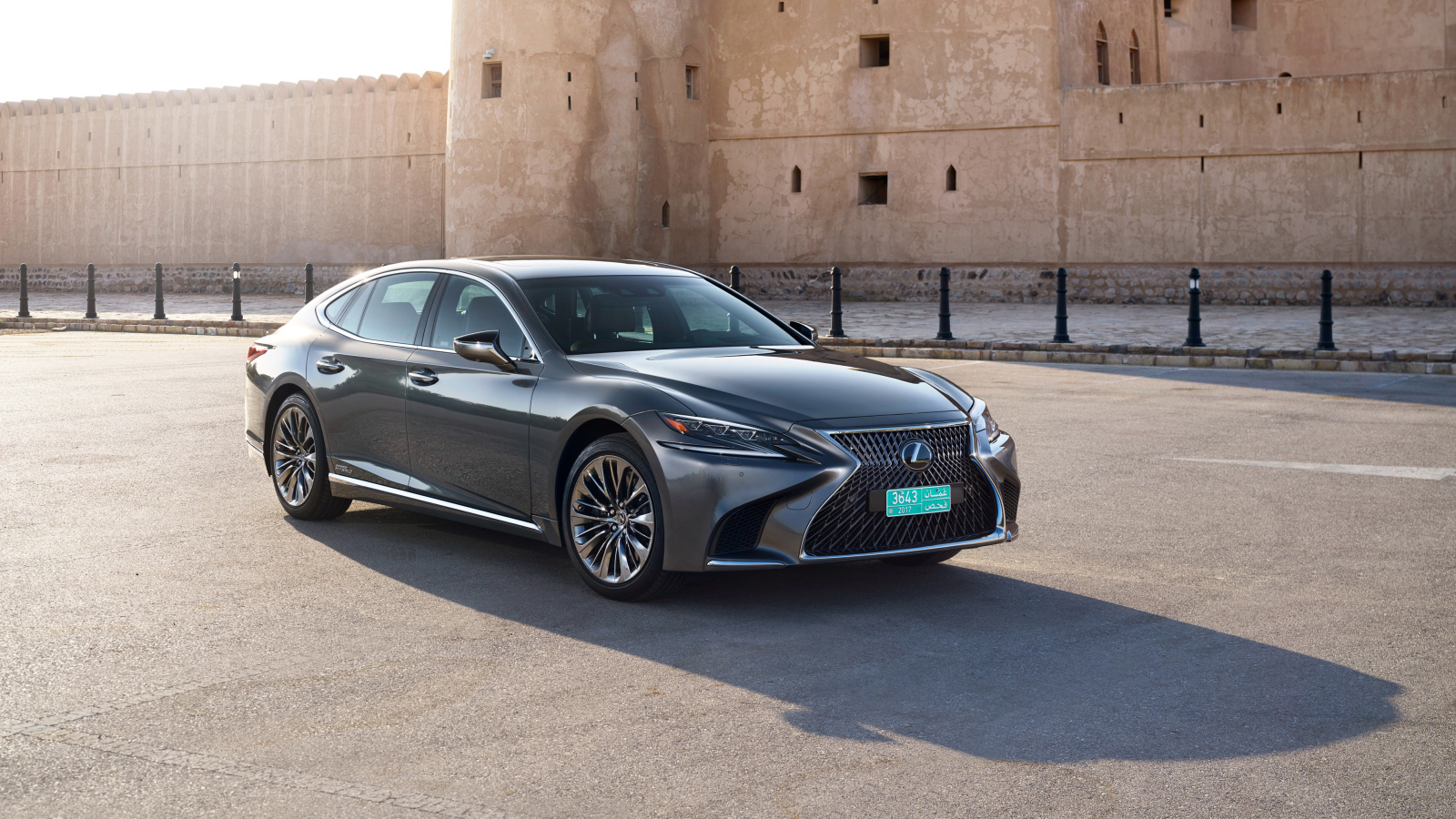 Стильный автомобиль Lexus LS 500h AWD, 2018 на фоне крепости