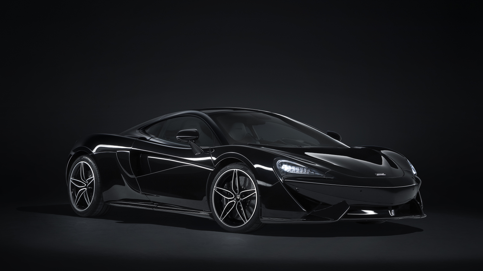 Черный автомобиль McLaren 570GT на сером фоне