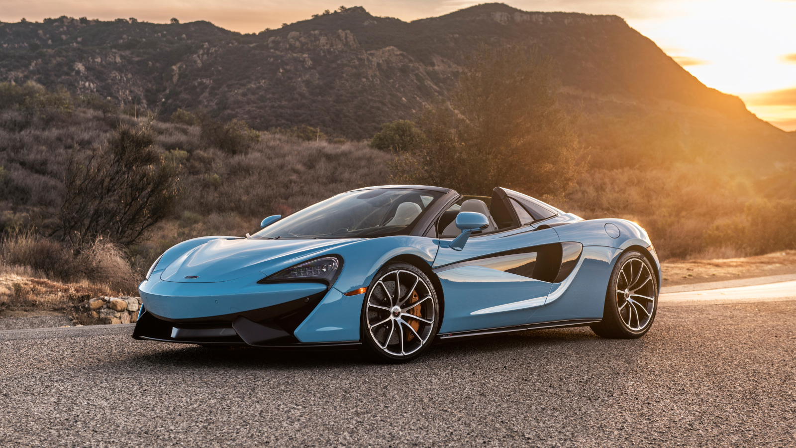 Голубой спортивный автомобиль  McLaren 570S Spider, 2018 на фоне солнца