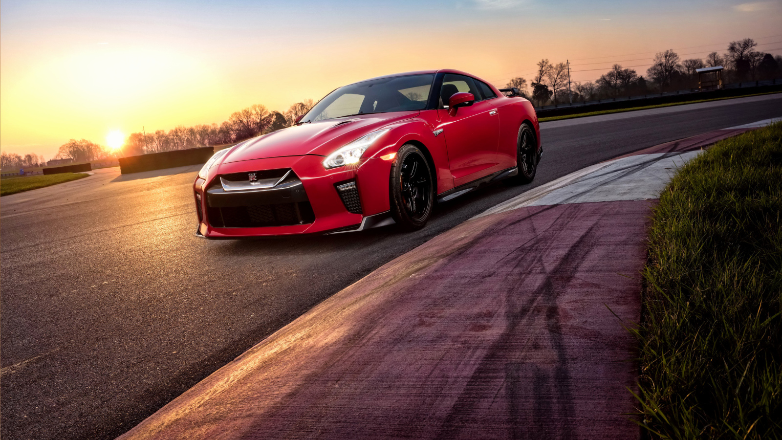 Красный автомобиль Nissan GT-R 2018 года на трассе на закате