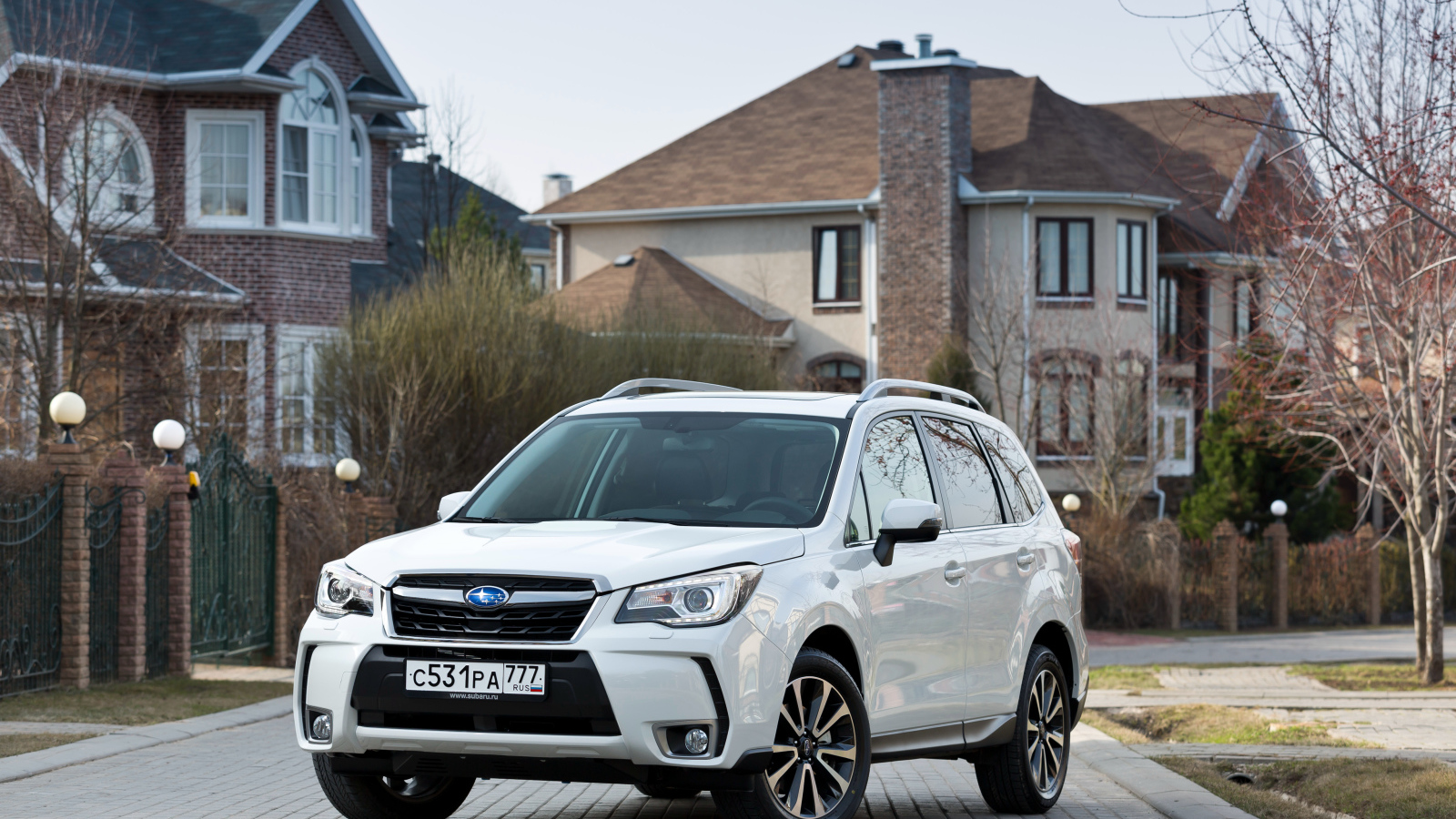 Белый автомобиль Subaru  Forester на улице у домов