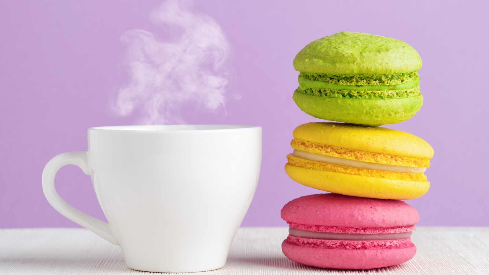 A colorful dessert macaroon with a cup of hot coffee on the table