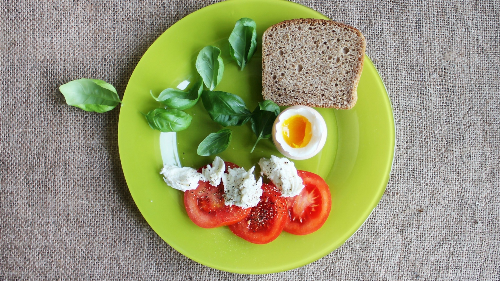 Легкий завтрак с помидорами, яйцом, кусочком хлеба и листьями базилика