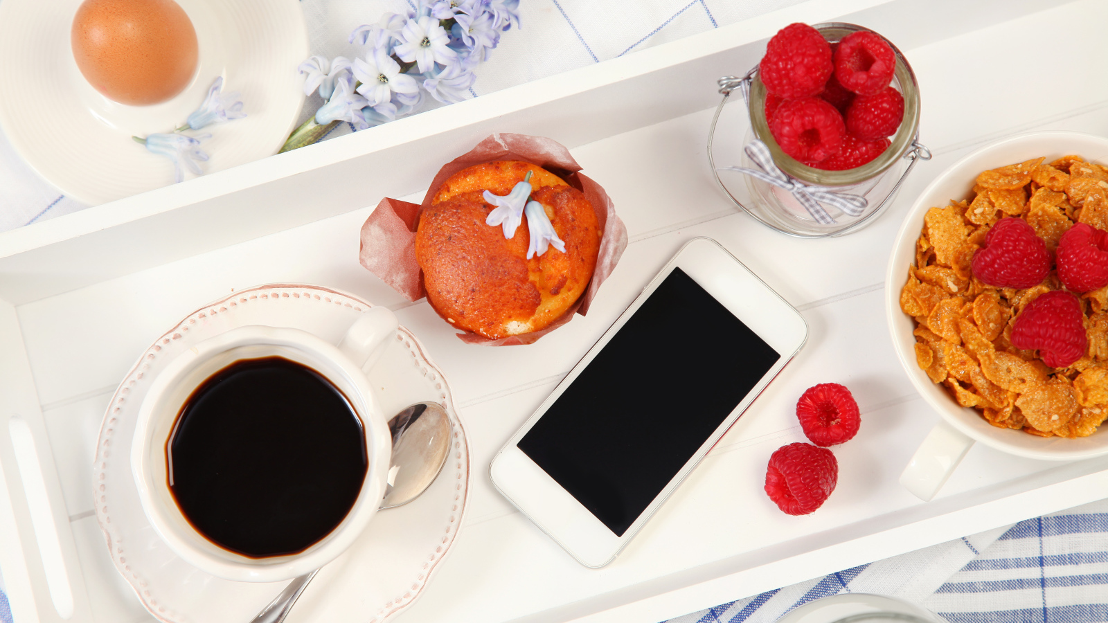 Кофе с кексом, хлопьями и малиной на столе со смартфоном 