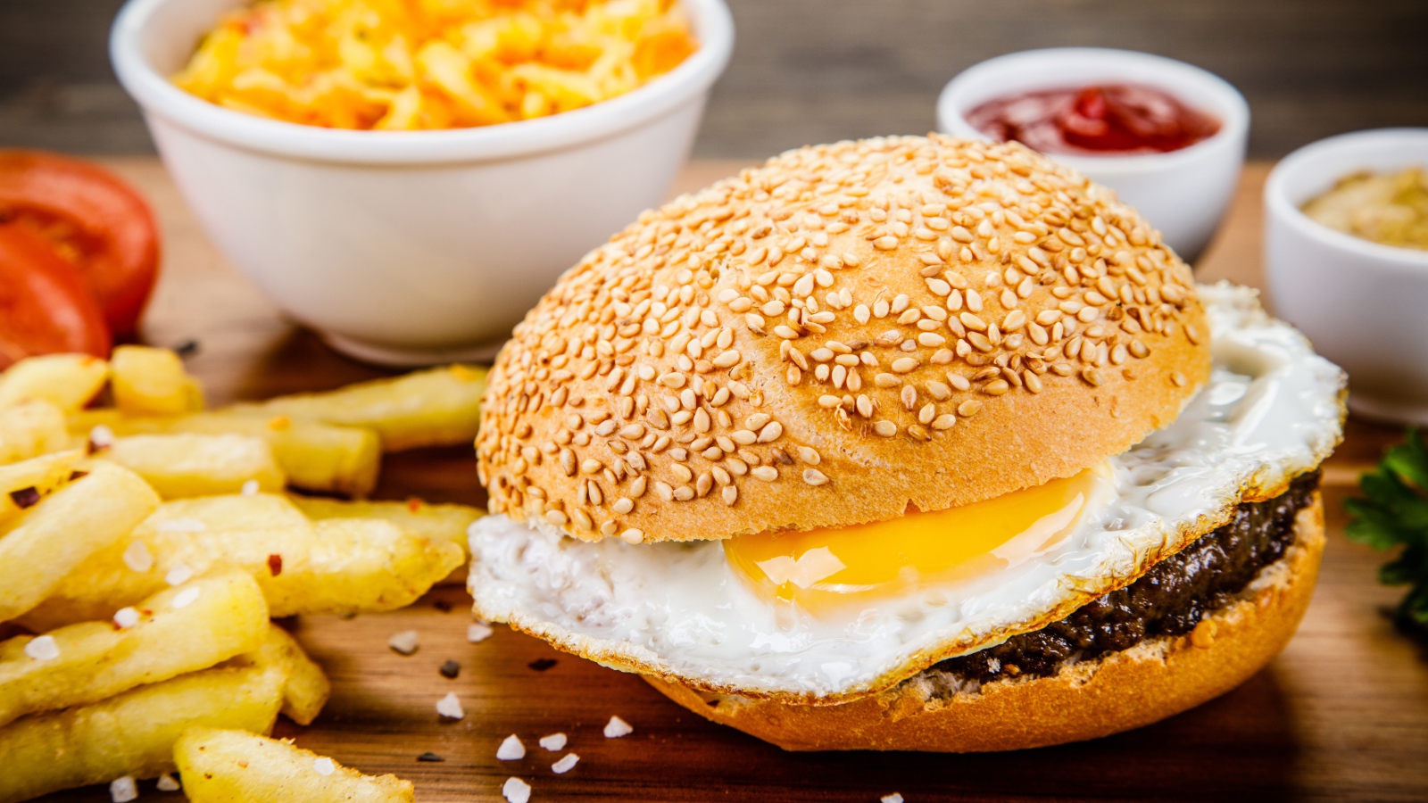 Гамбургер с яичницей на столе с картофелем фри и соусом