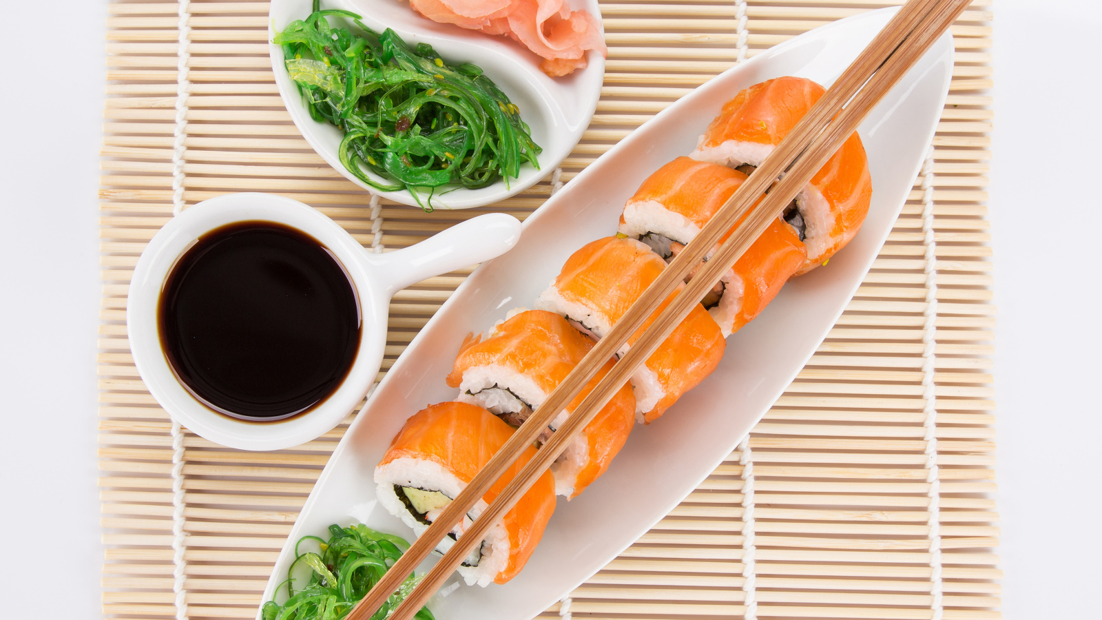 Японские суши на столе с соевым соусом и имбирем с салатом