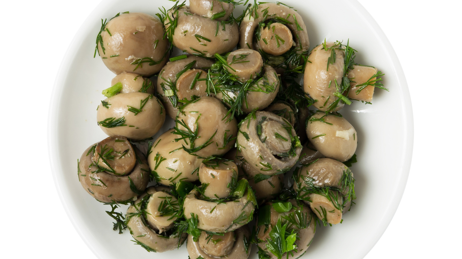 Маринованные шампиньоны с зеленью в белой тарелке на белом фоне 