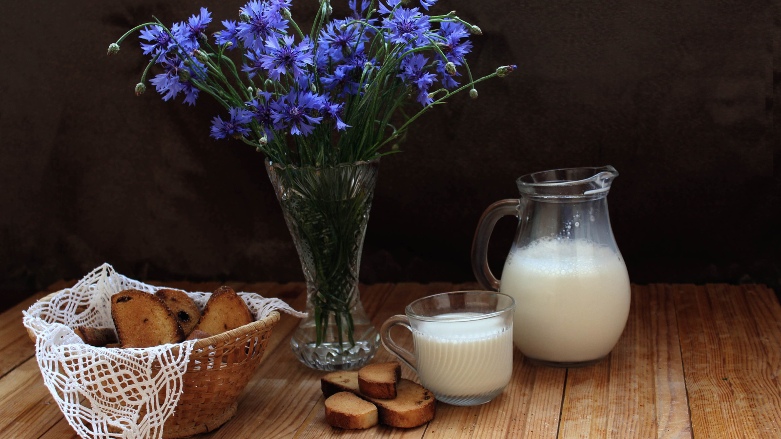 Молоко с сухариками на столе с букетом синих васильков