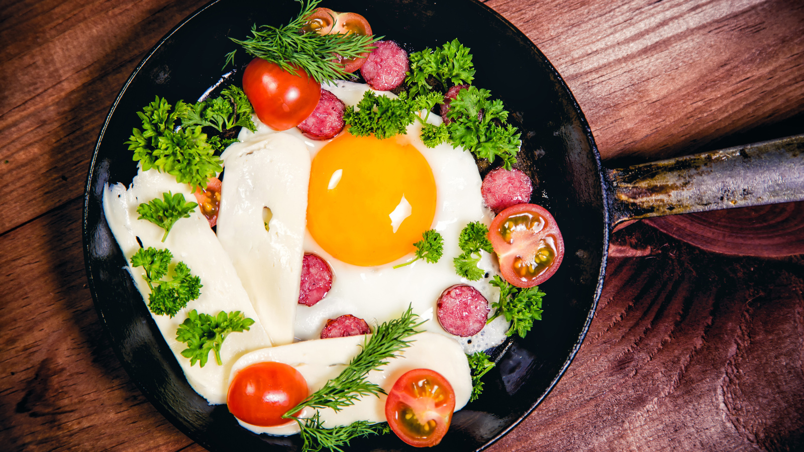 Яичница с колбасой, сыром,  помидорами и зеленью на сковороде