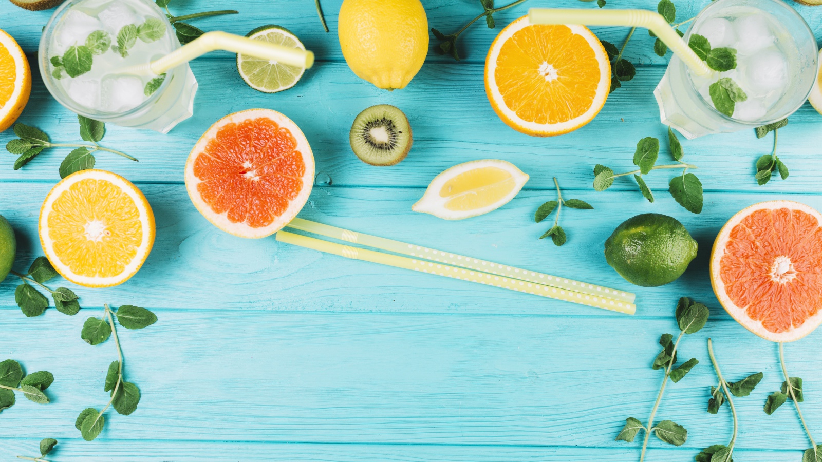 Цитрусовые фрукты на голубом столе с мятой и лимонадом