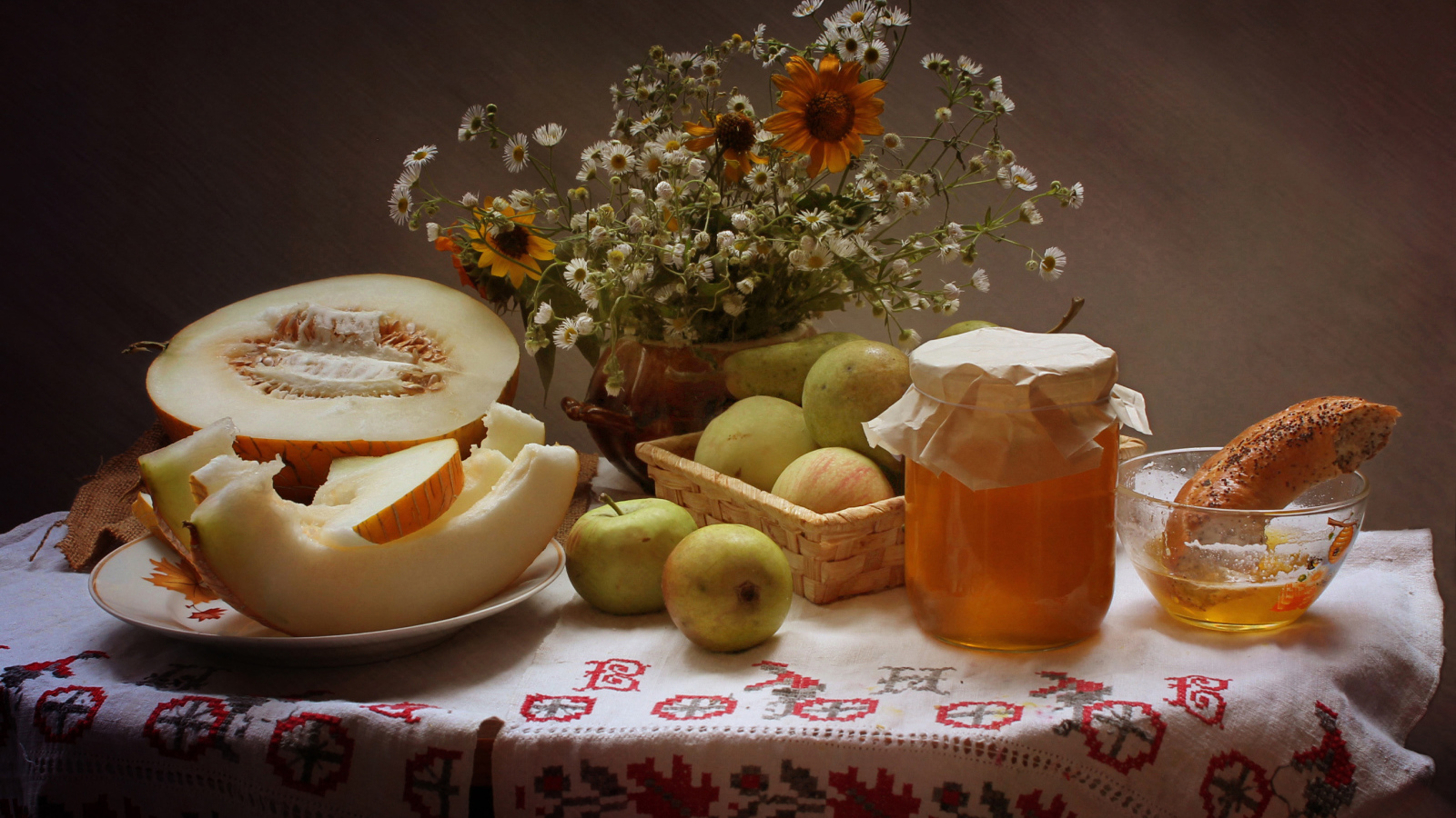 Сочная дыня с яблоками на столе с медом и букетом цветов