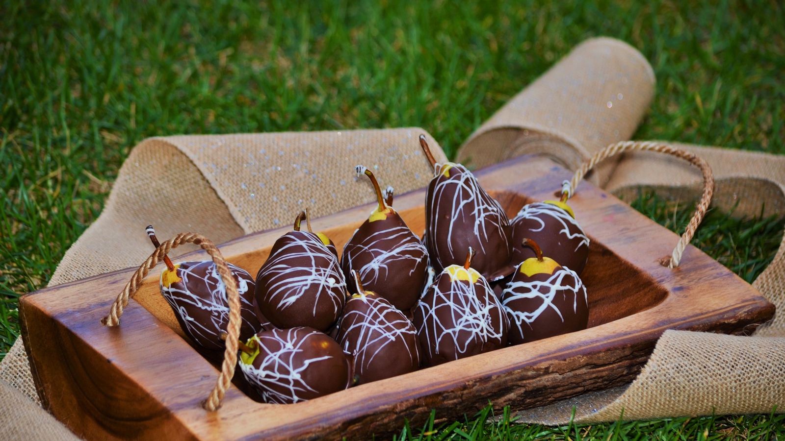 Груши в шоколадной глазури стоят на зеленой траве