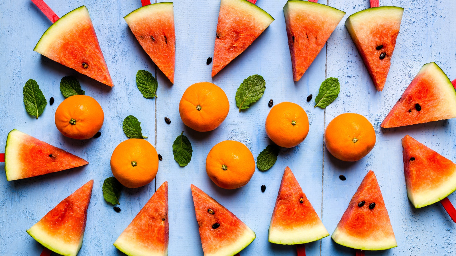 Кусочки арбуза на палочках на столе с мандаринами