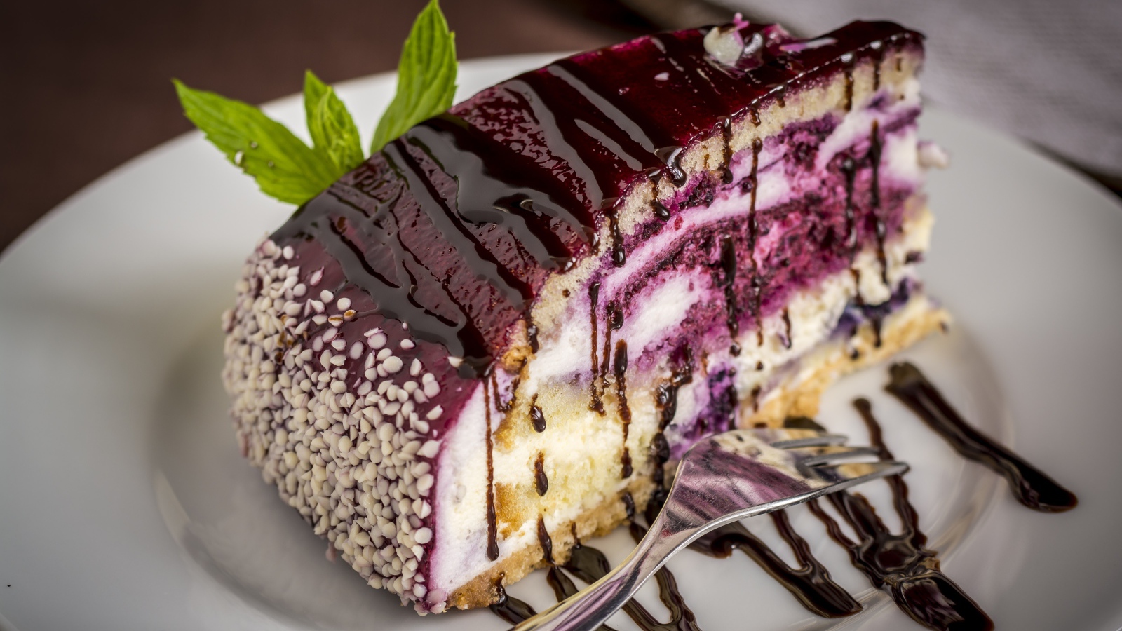 Кусок черничного пирога с джемом на белой тарелке с вилкой