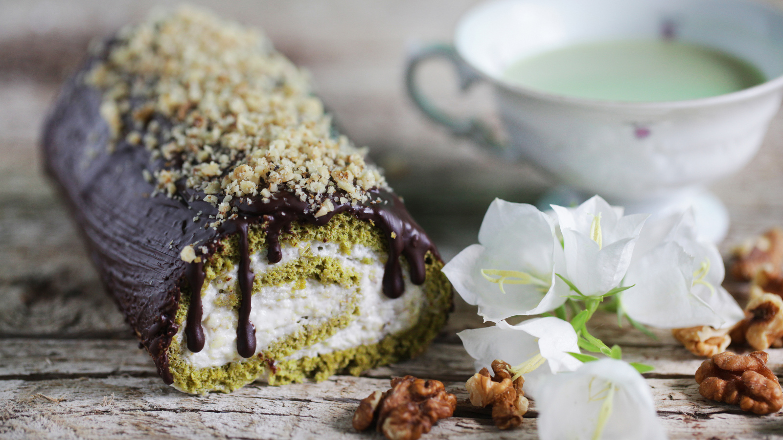 Аппетитный сладкий рулет с шоколадом на столе с белыми цветами колокольчика