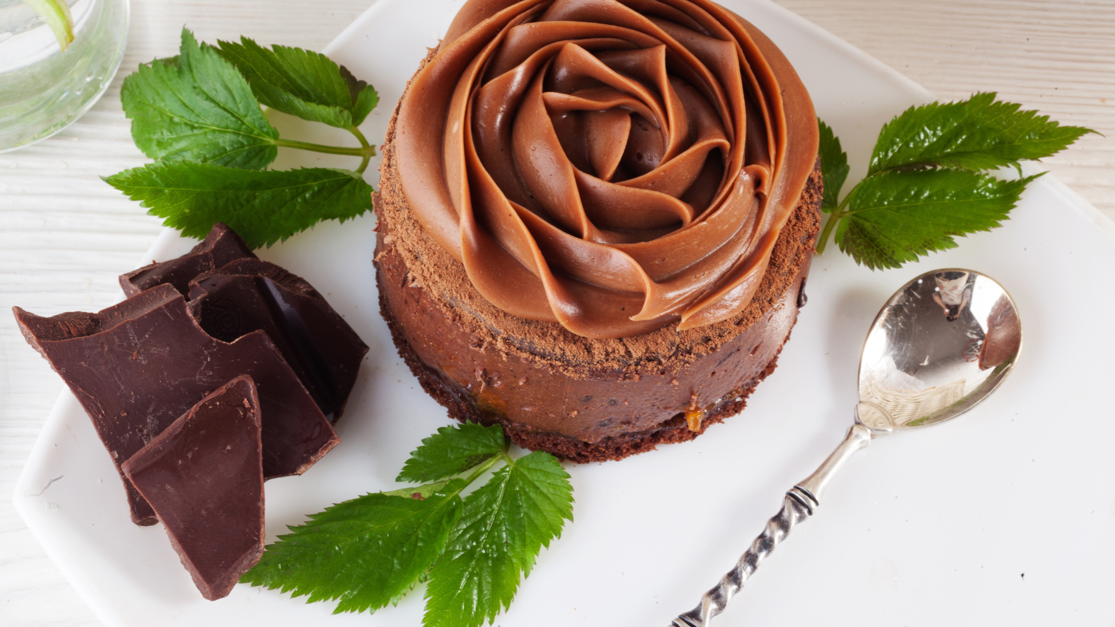 Пирожное с шоколадной кремовой розой на тарелке