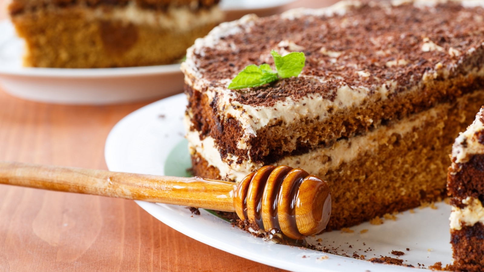 Торт с кремом и шоколадом на тарелке с ложкой для меда