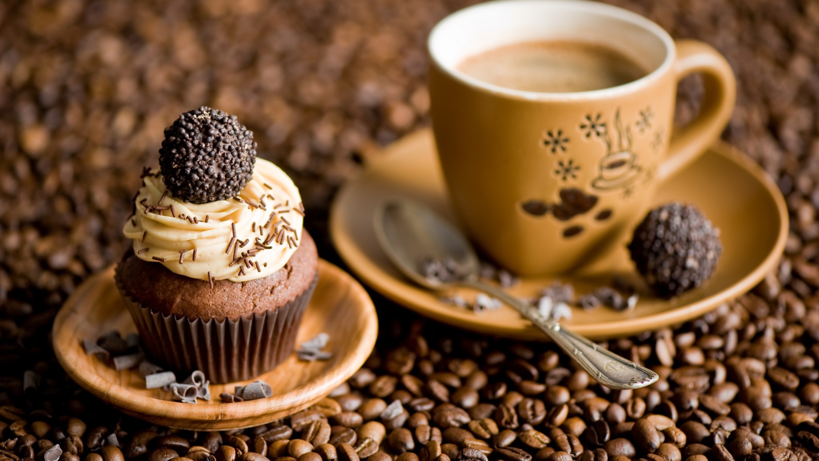 Кекс с кремом и чашкой кофе стоят на кофейных зернах 