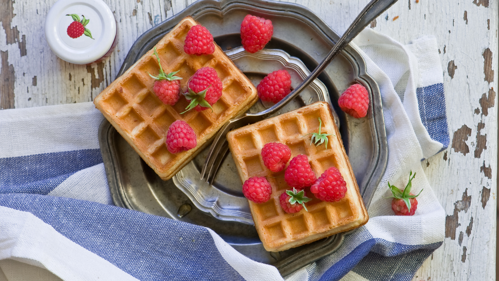 Сладкие вафли с ягодами малины на столе 