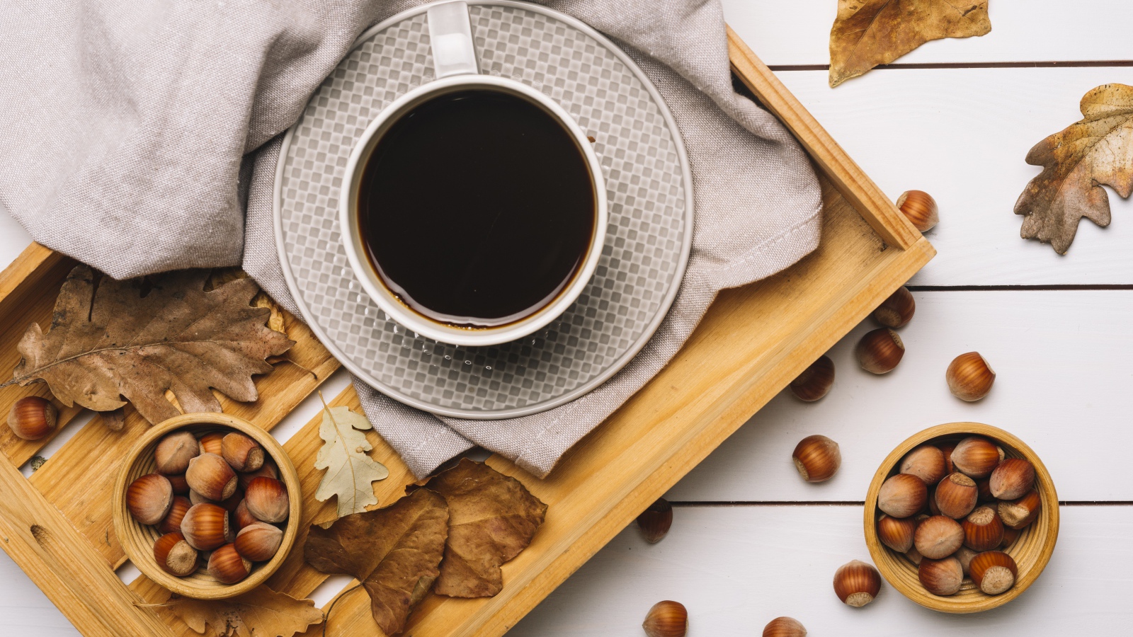 Чашка кофе на столе с лесными орехами и желтыми листьями